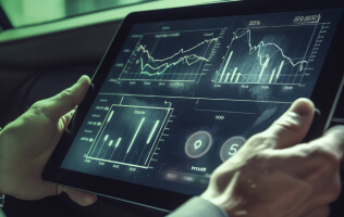 Hands holding a tablet displaying financial charts and data analysis.