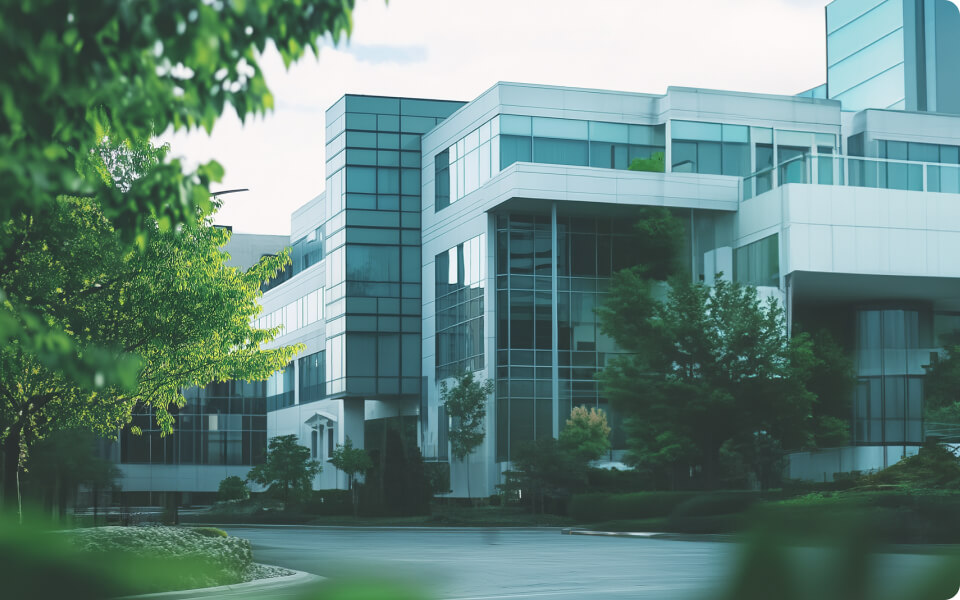 Modern glass and steel office building with surrounding greenery.